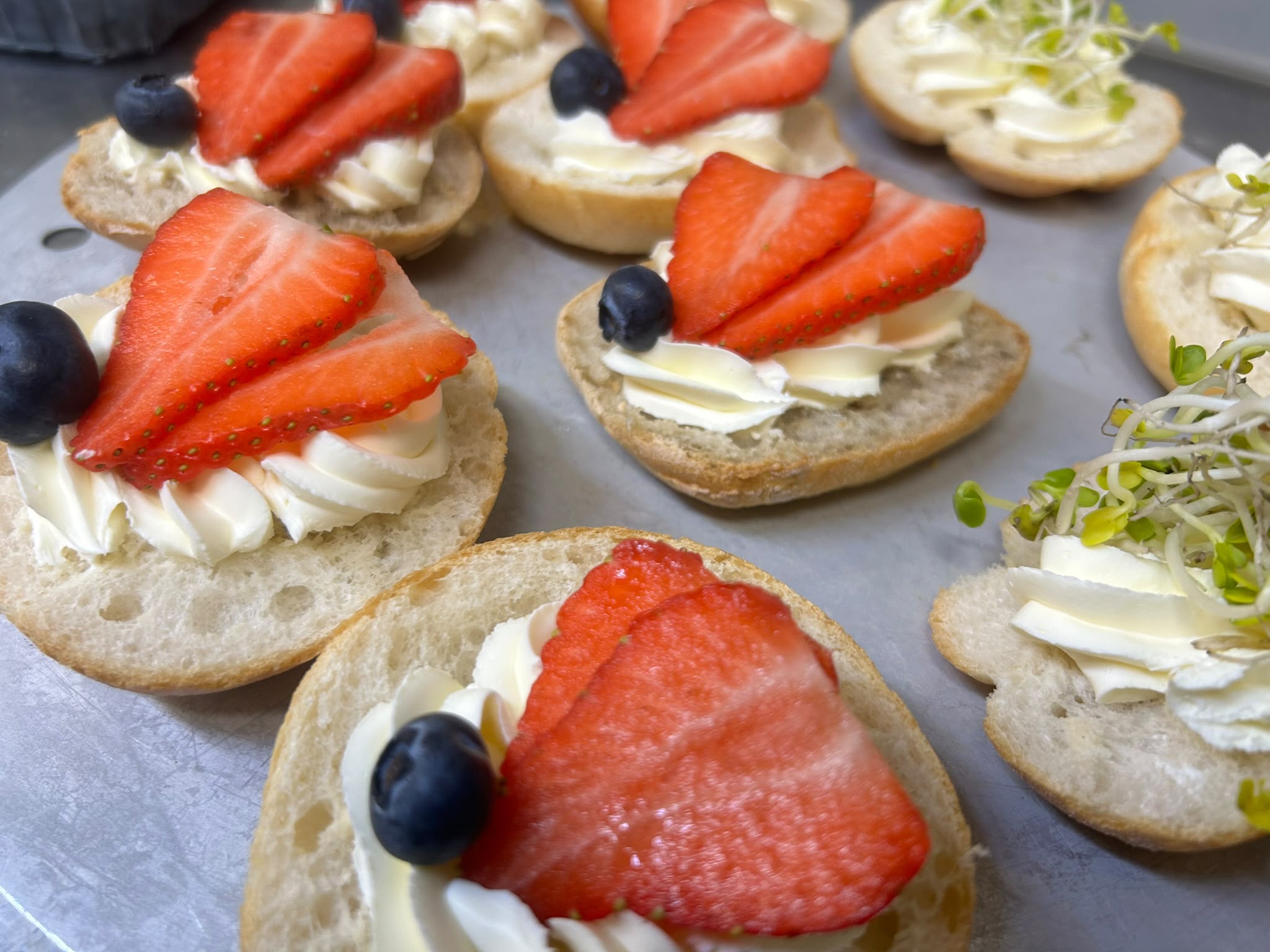 Fein belegte Brötchen mit Erdbeeren, Beeren und Kräutern